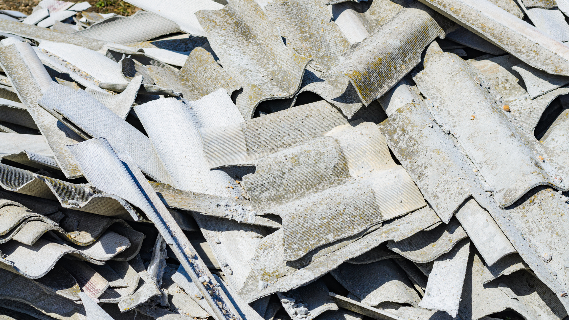 Pile of broken white and gray roof tiles with debris scattered across the surface