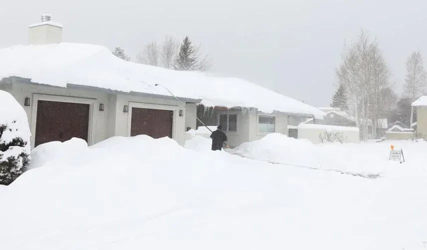 Snow-covered suburban house and driveway buried in deep snow during a heavy winter storm.