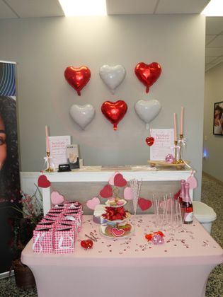 Pink dessert table with heart balloons and Valentine decorations in a party room