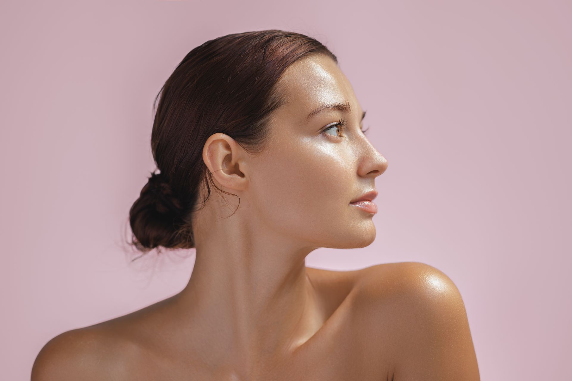 Profile portrait of a person with dark hair against a pink background