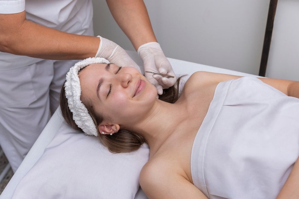 Esthetician giving a facial massage to a client lying on a treatment table