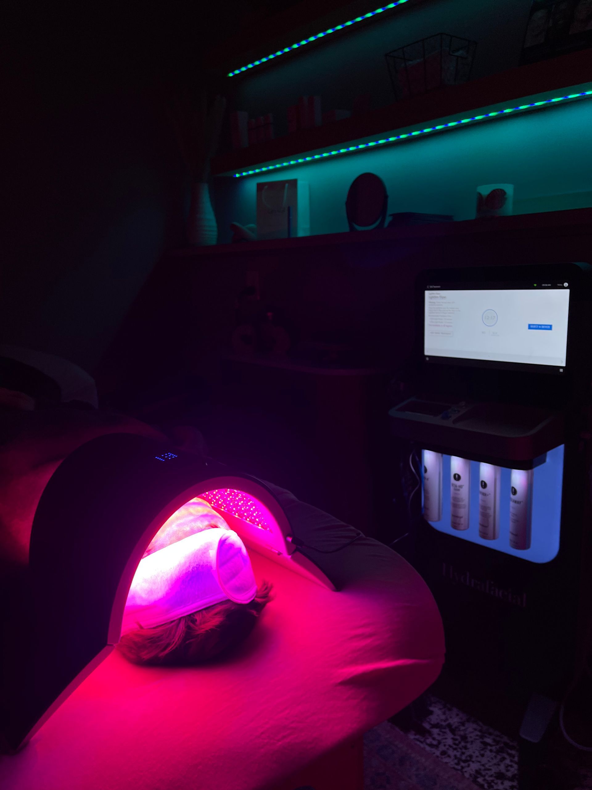 Person under pink glow in a dark room with a laptop and teal LED lighting