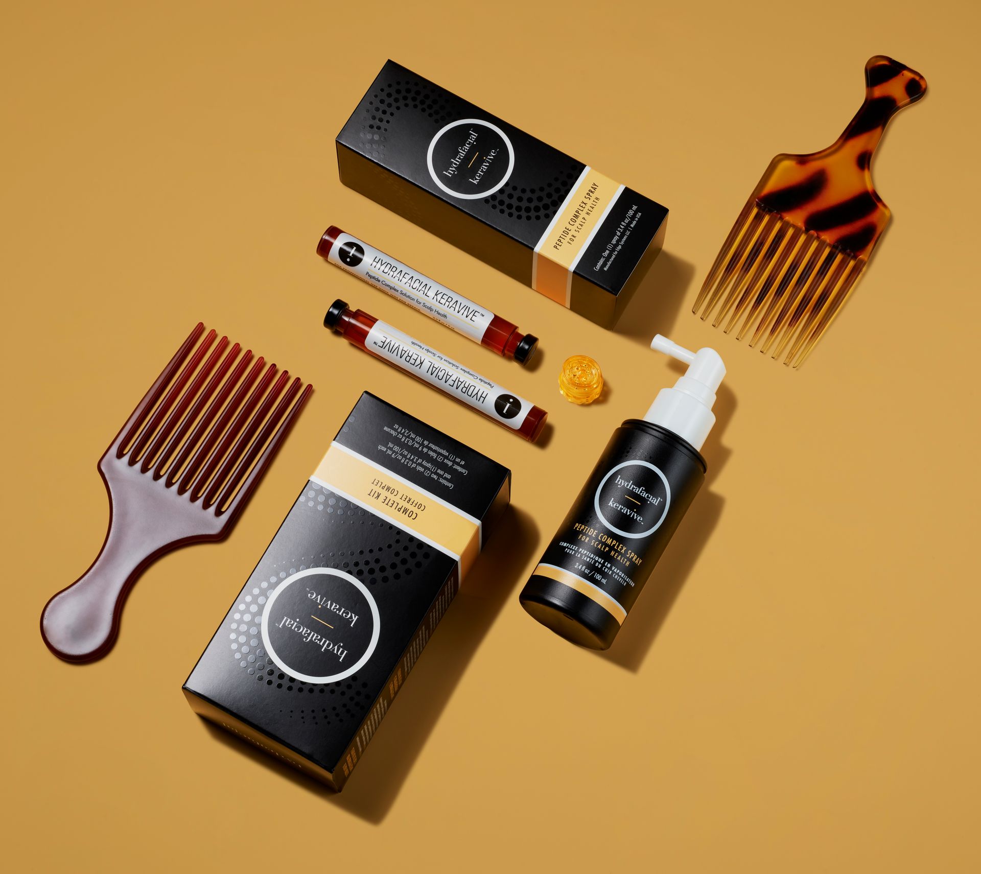 Hair care products and combs arranged on a mustard background with black, white, and tortoiseshell packaging