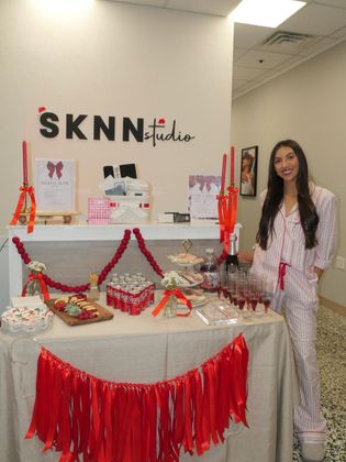 Woman stands beside a decorated red-and-white display table with 