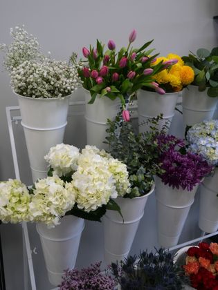 White buckets of assorted colorful flowers arranged on stepped shelves