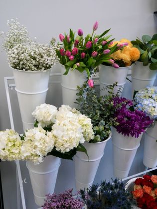 White metal buckets of assorted flowers in white, pink, purple, yellow, and red on display