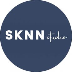 A pink circle with the words sknn studio written inside of it.