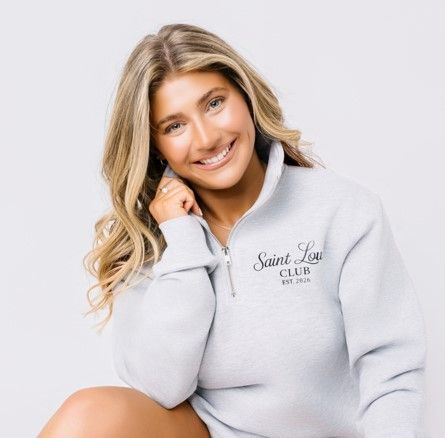 Smiling blonde woman in a light gray quarter-zip top against a white background