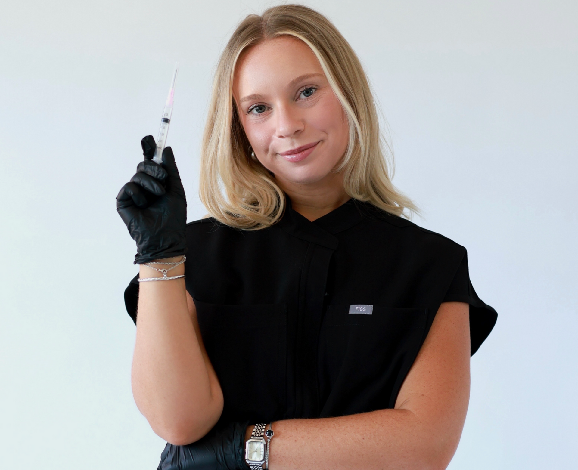 Woman in black gloves holding a syringe against a plain white background