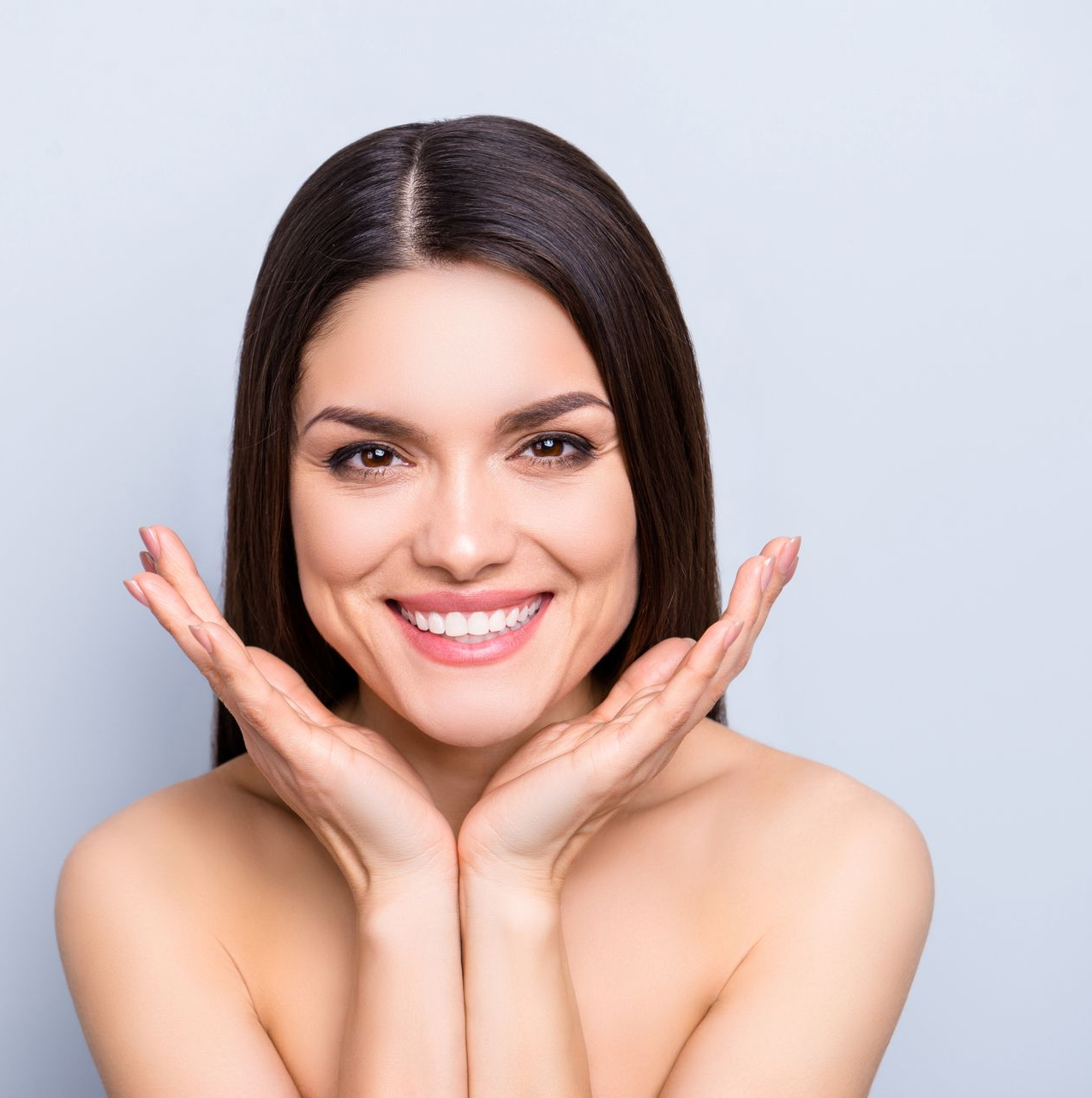 Smiling person with hands framing face against a light background