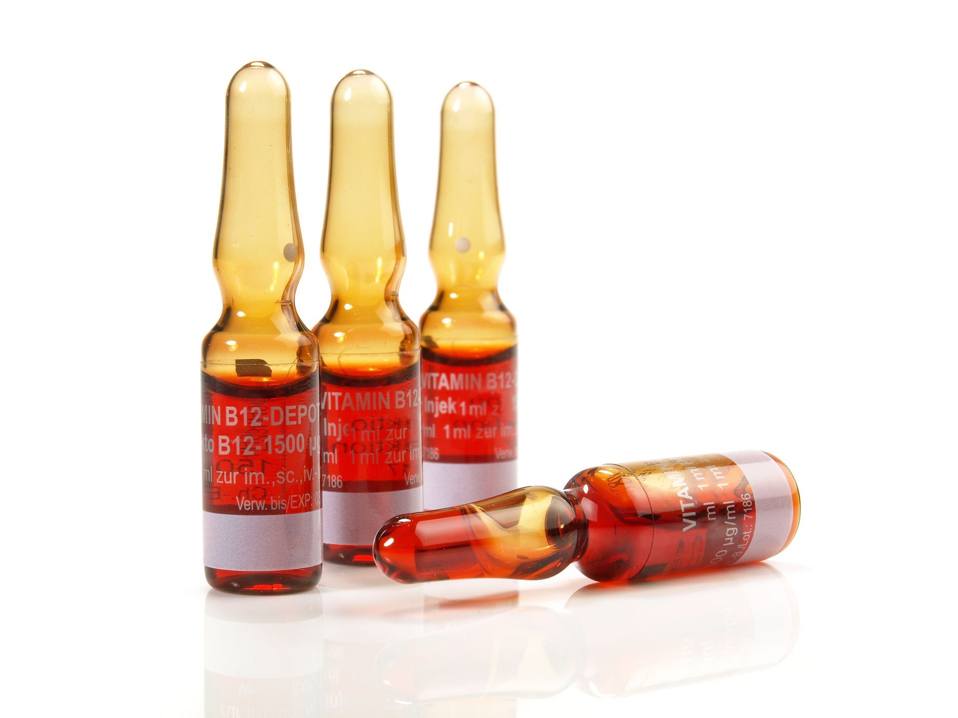 Three amber medicine ampoules standing and lying on a white surface