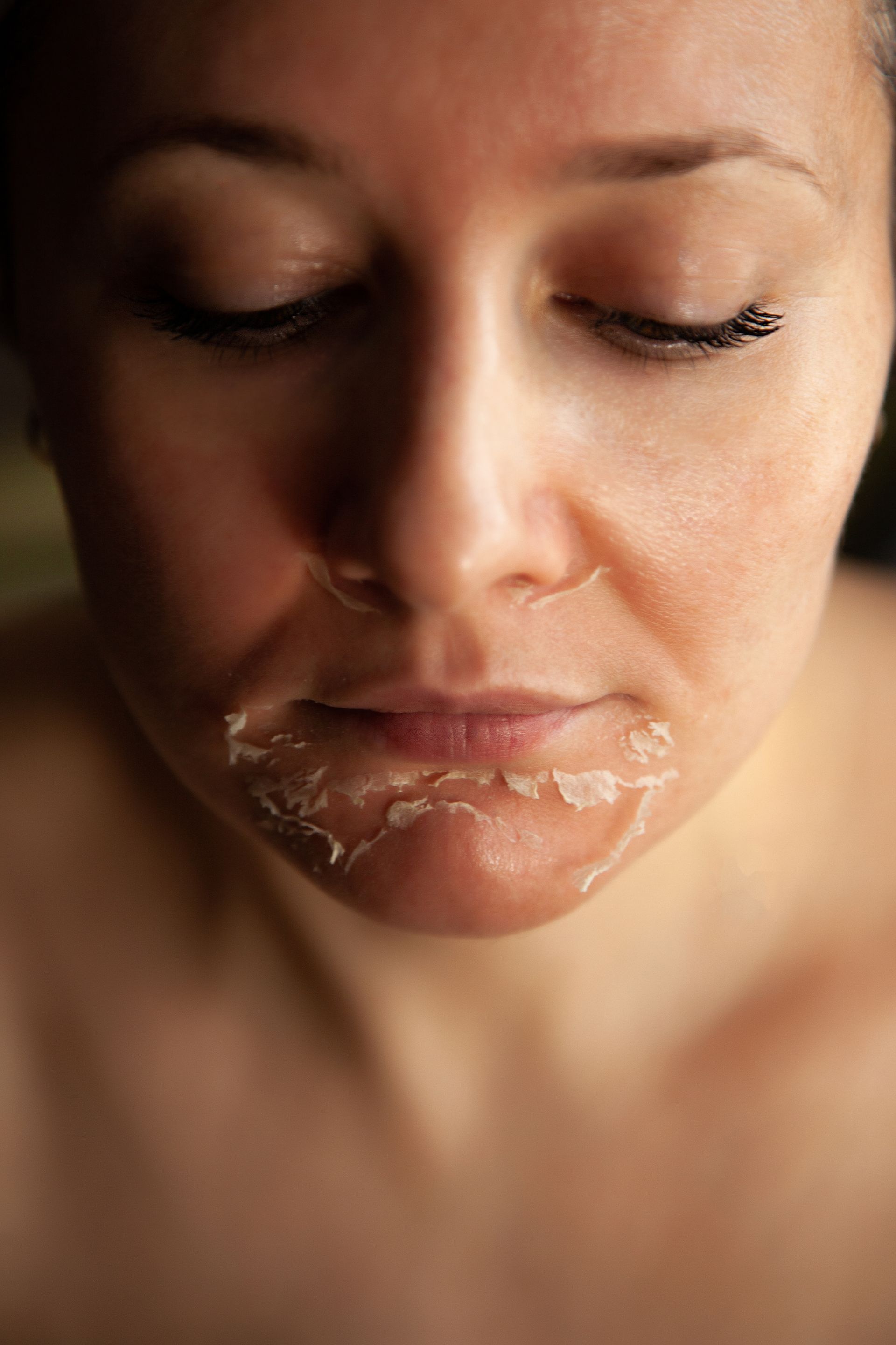 Close-up of a person’s face with a white cream mask around the mouth and chin, eyes closed
