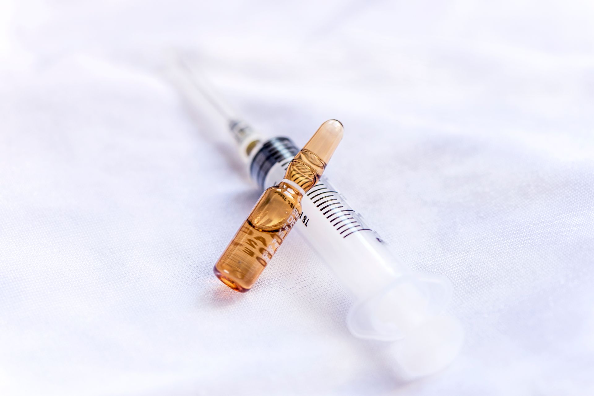 Two syringes, one filled with amber liquid, on a white background