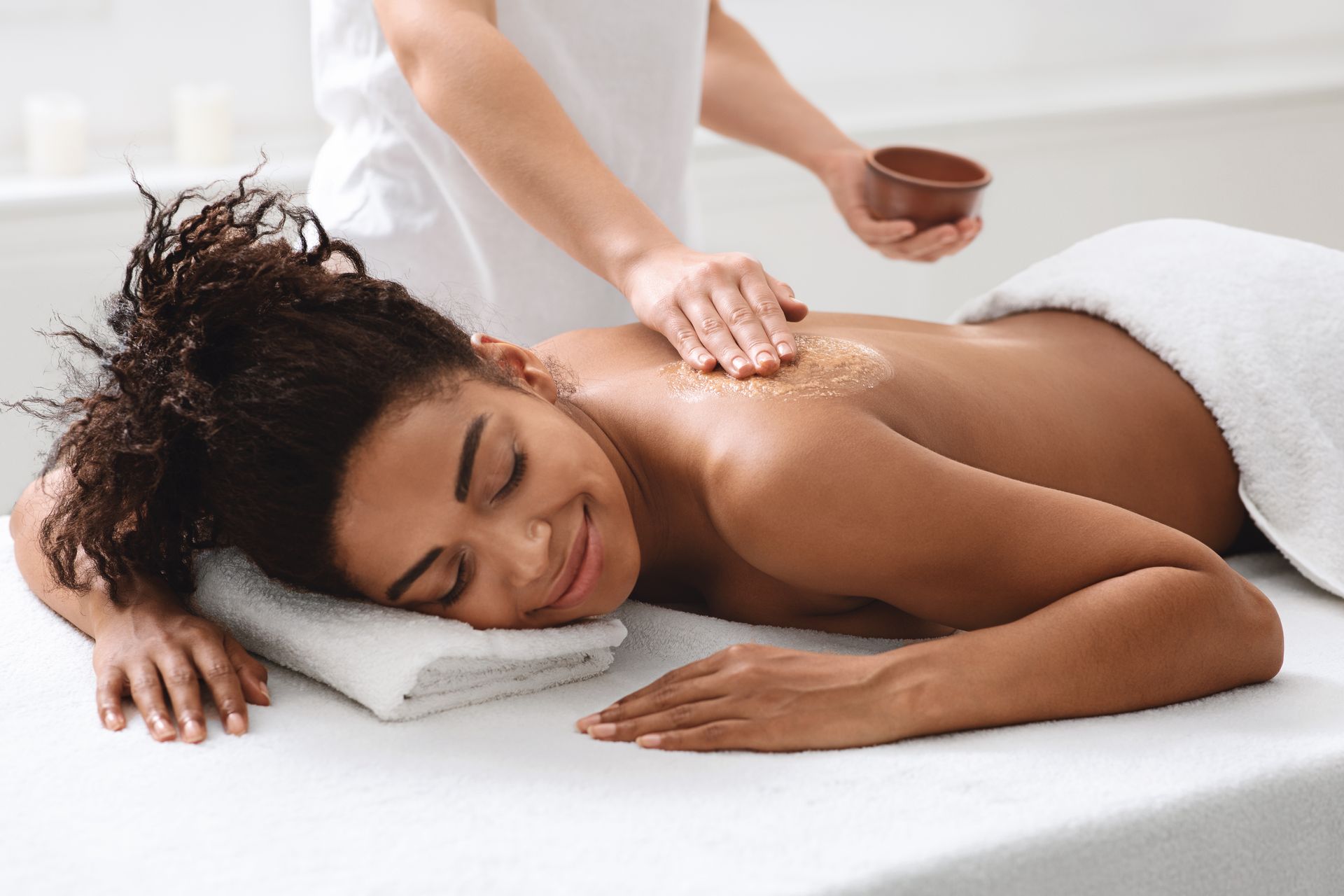 Woman receiving a back massage on a spa table, resting on a white towel