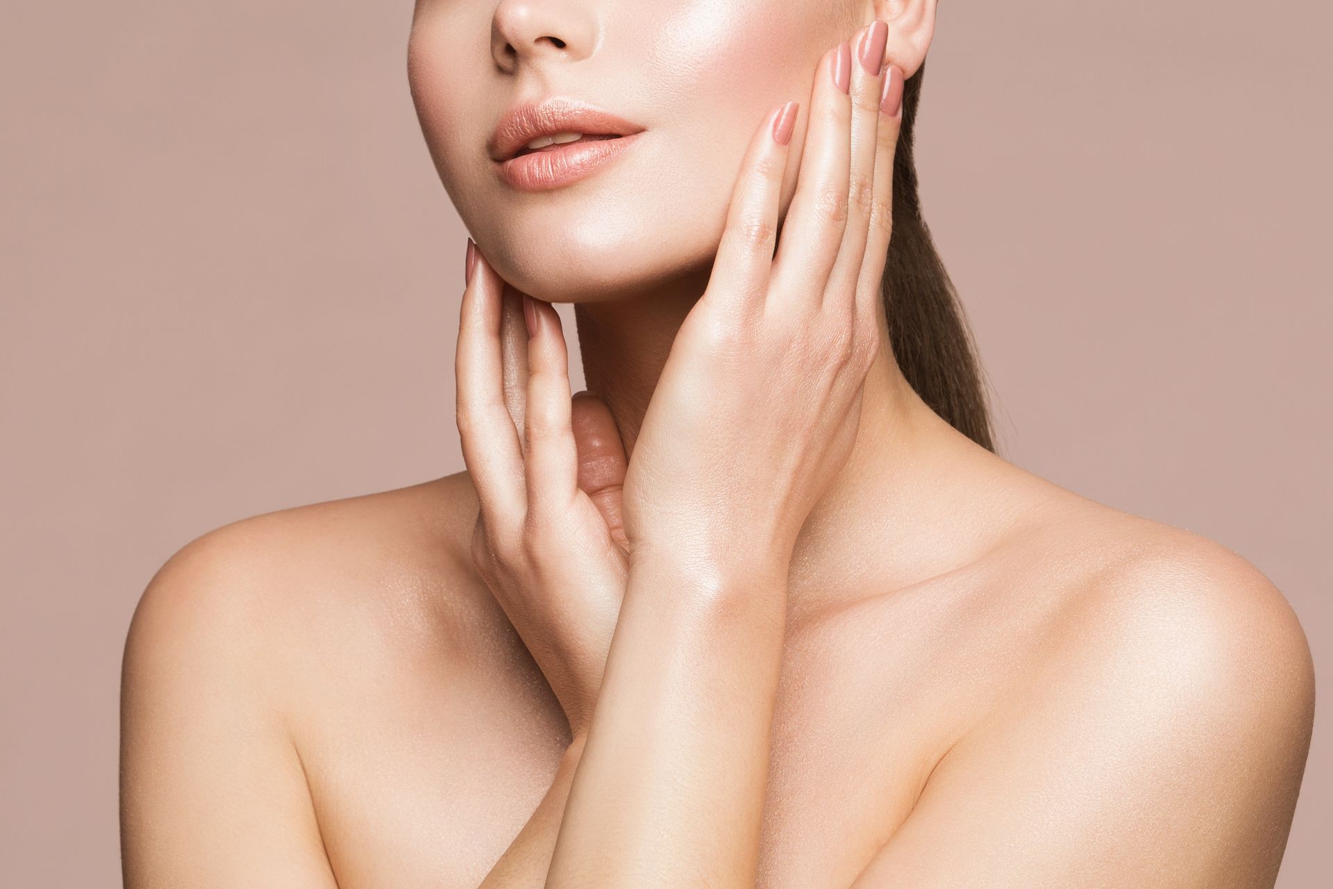 Close-up of a person touching their face and neck against a soft beige background.