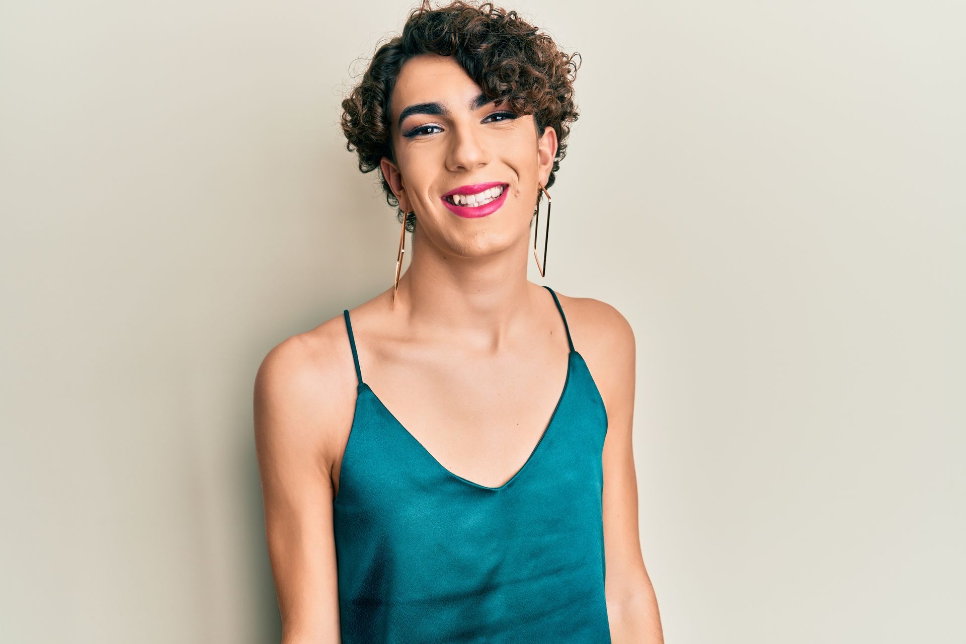Smiling person in a teal camisole against a beige background.