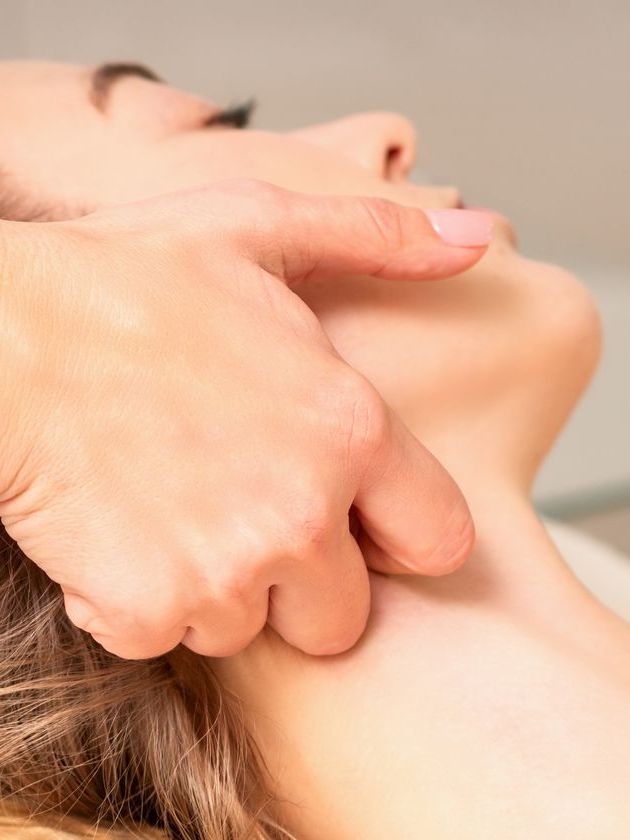 Close-up of hands massaging a person's jaw and neck in a spa setting