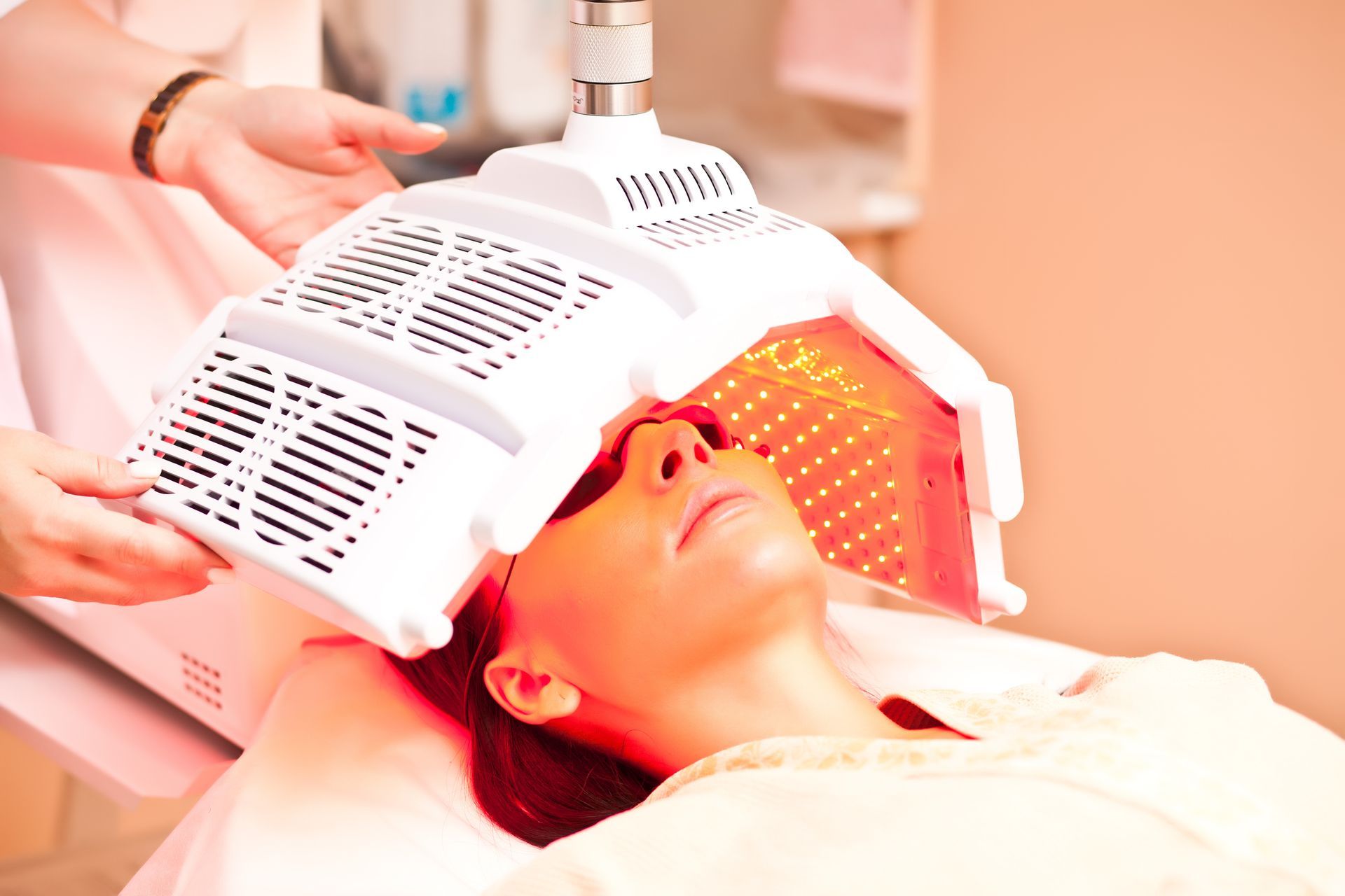 Person receiving red LED light therapy on face while reclining on a treatment bed