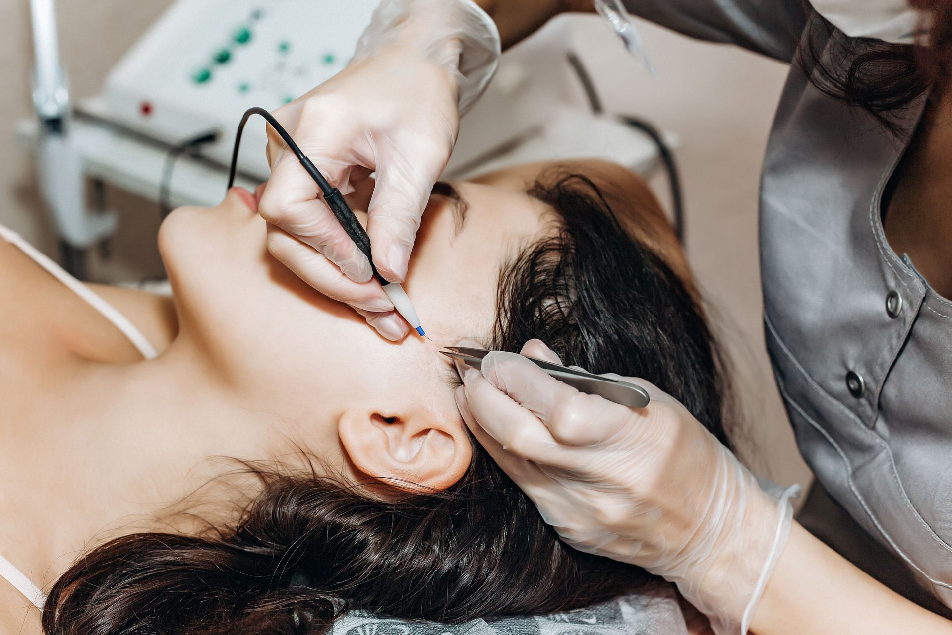 Cosmetic procedure on a woman’s eyebrow with a handheld tool in a clinic setting
