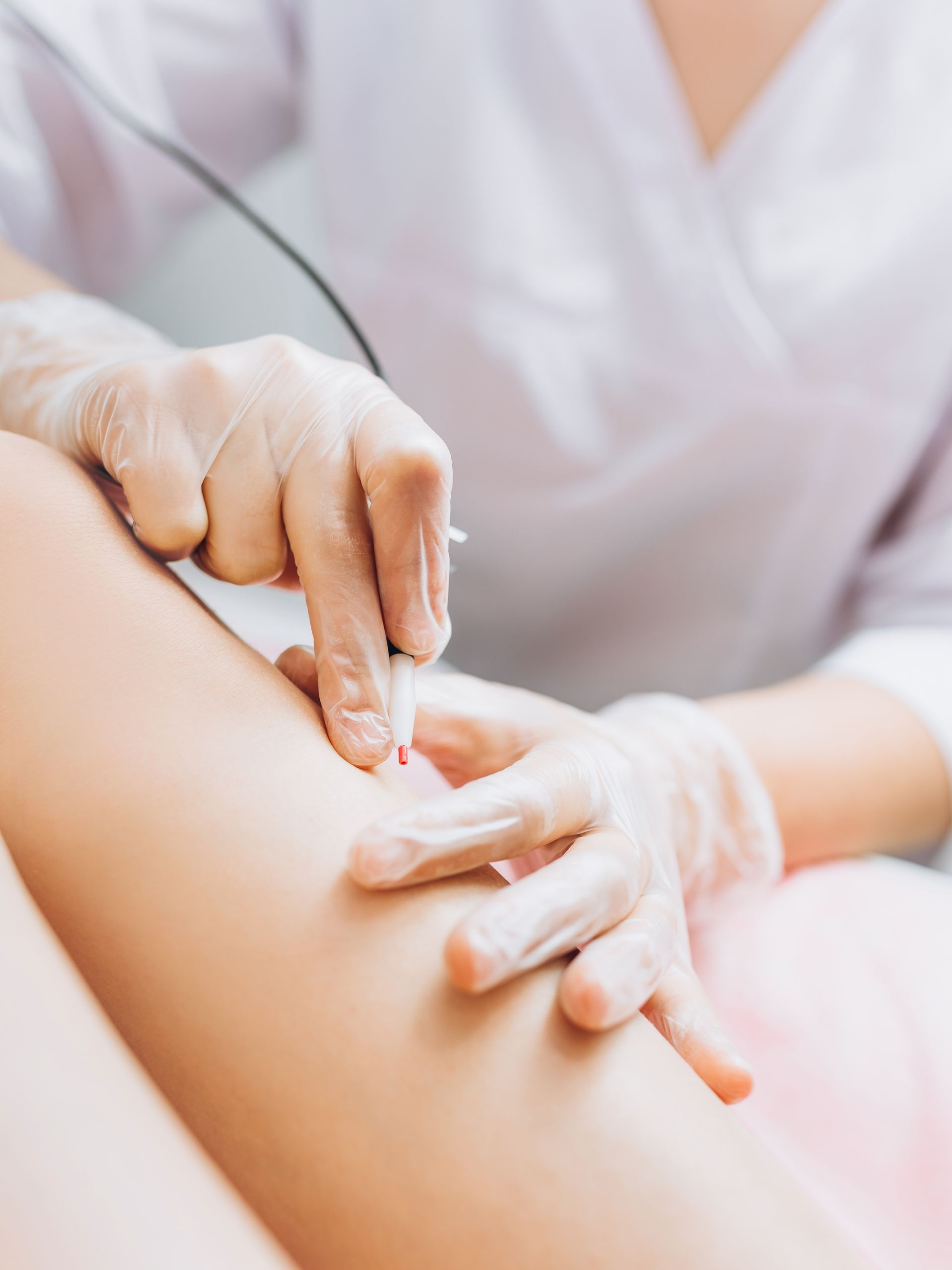 Hands applying lotion to a person’s arm in a soft, close-up spa setting