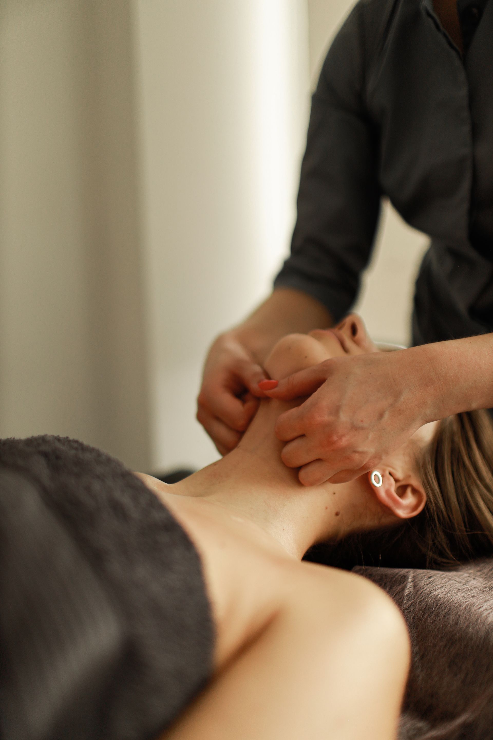 Person receiving a massage on the neck and jaw in a spa setting