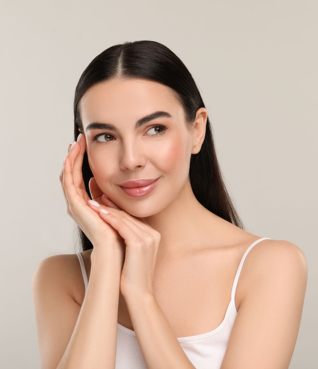 Portrait of a woman with dark hair, resting her face on her hand against a beige background