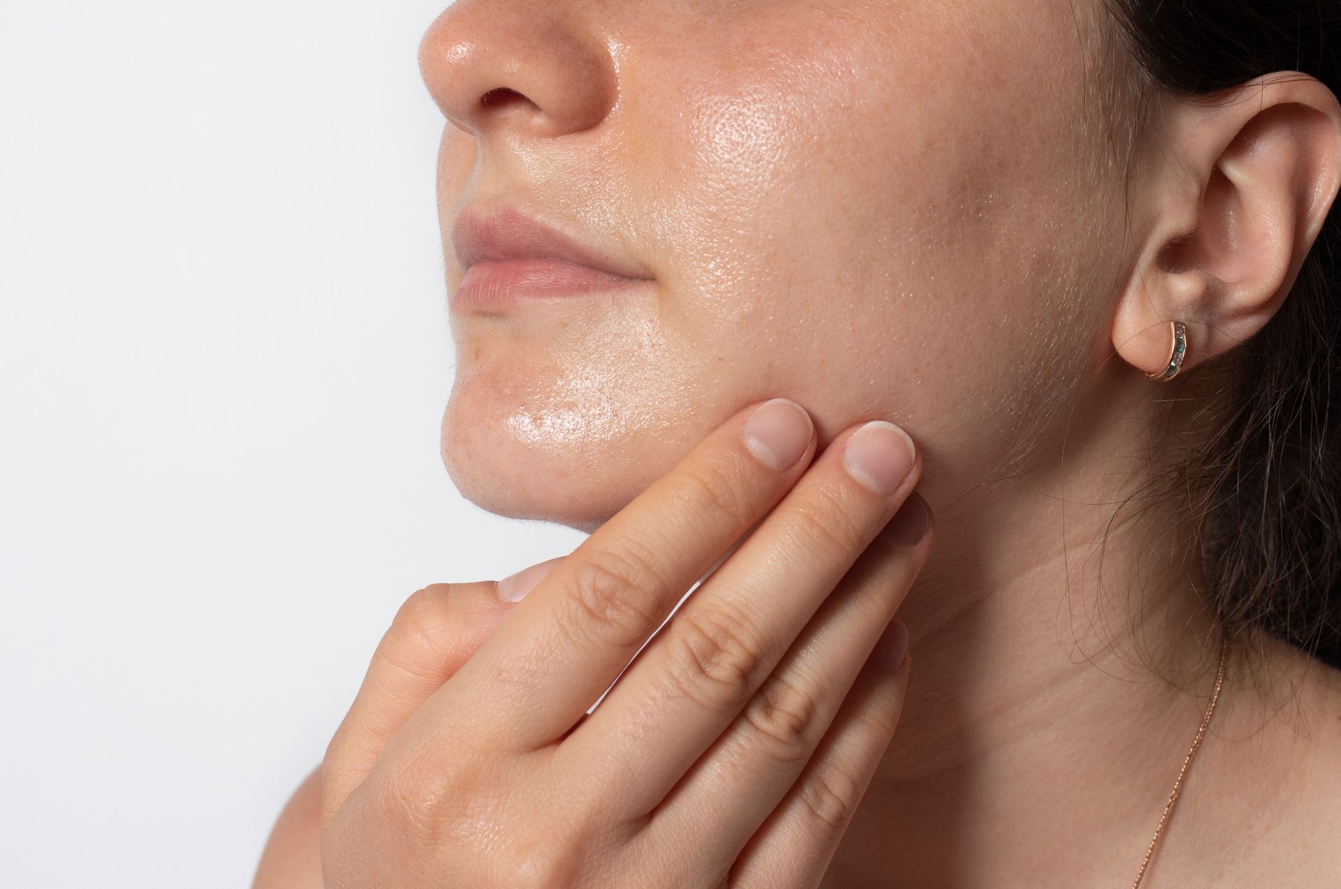 Person touching a shiny jawline and chin, highlighting facial skin texture