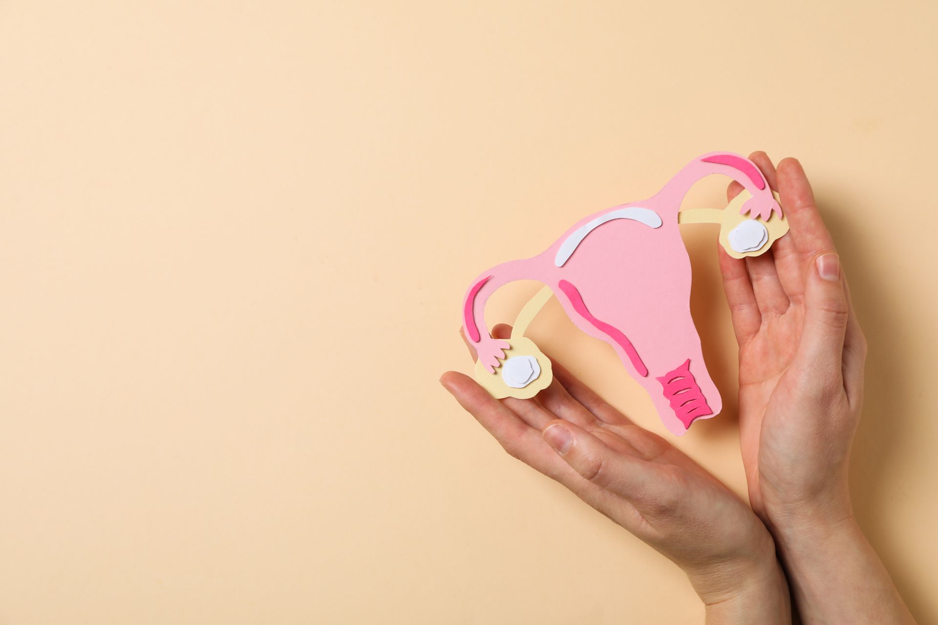 Hands holding pink children's sunglasses with white flower accents on a beige background