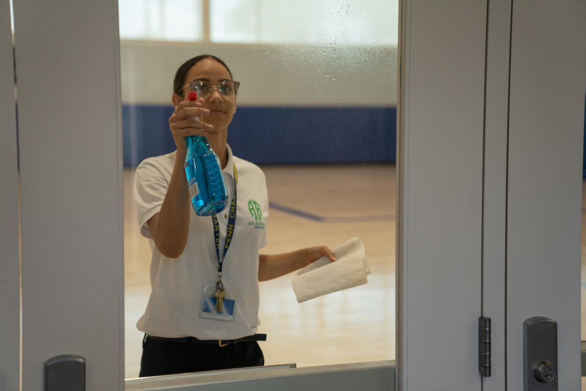 A woman is cleaning a window with a mop in an office.
