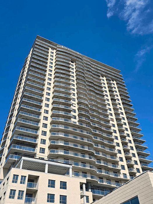 Tall modern high-rise apartment building against a bright blue sky