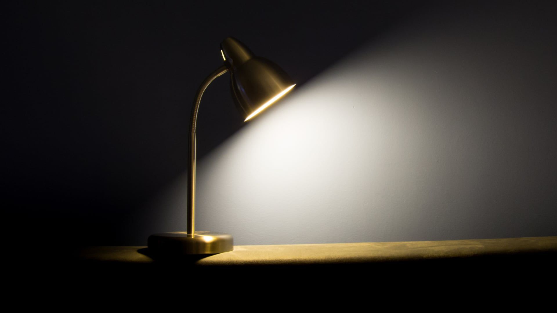 Desk lamp casting a warm beam of light across a dark surface