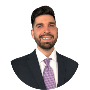 Headshot of a smiling man in a dark suit with a white shirt and lavender tie on a white background