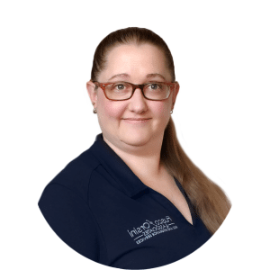 Portrait of a person in glasses and navy scrubs, smiling against a white background