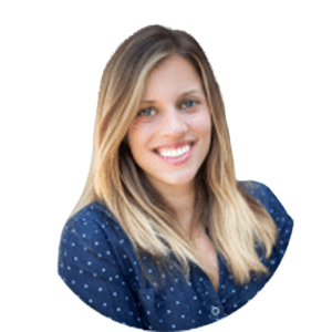 Smiling woman in a navy blue polka-dot blouse against a white background