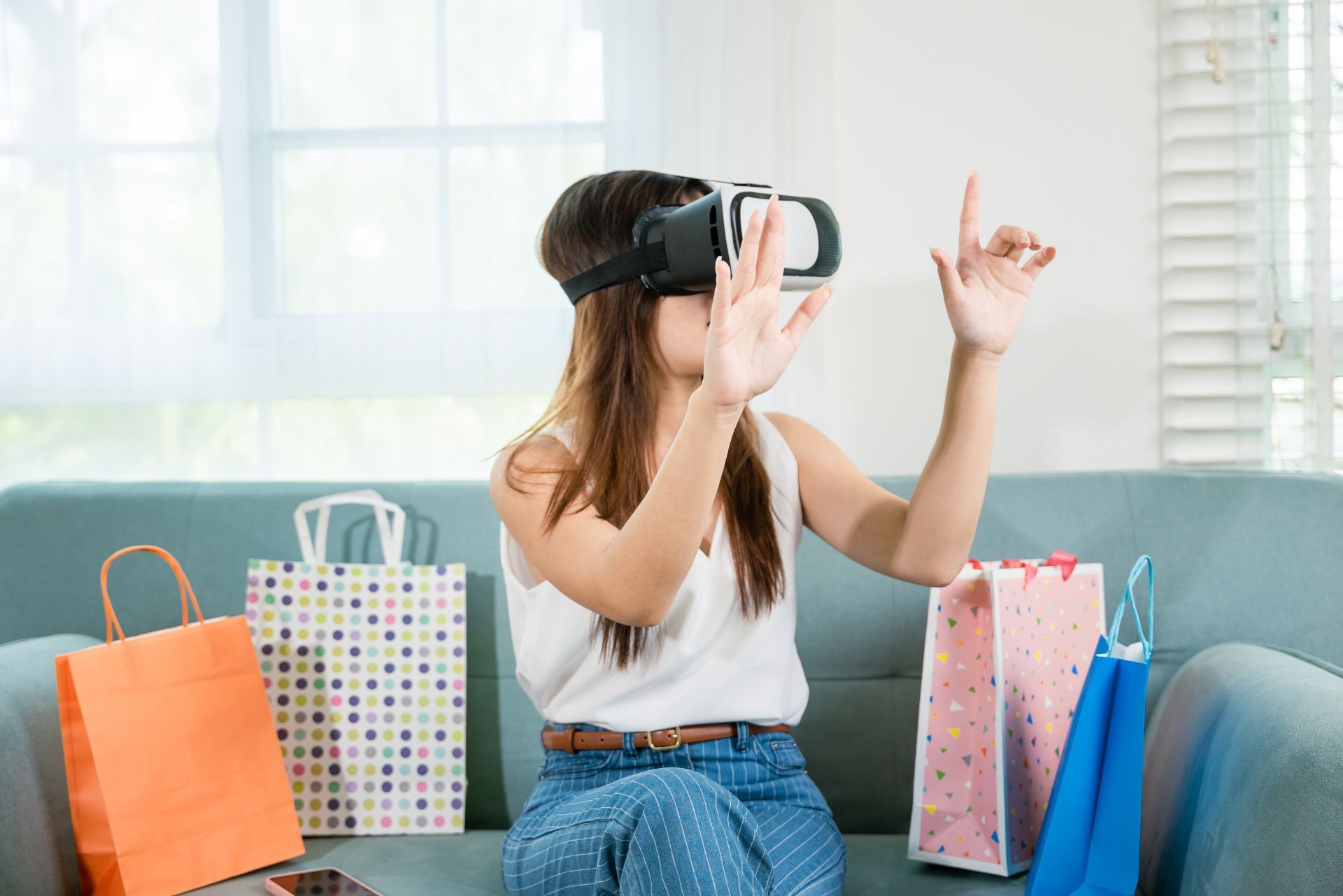 Person using a VR headset while sitting on a couch, surrounded by colorful shopping bags