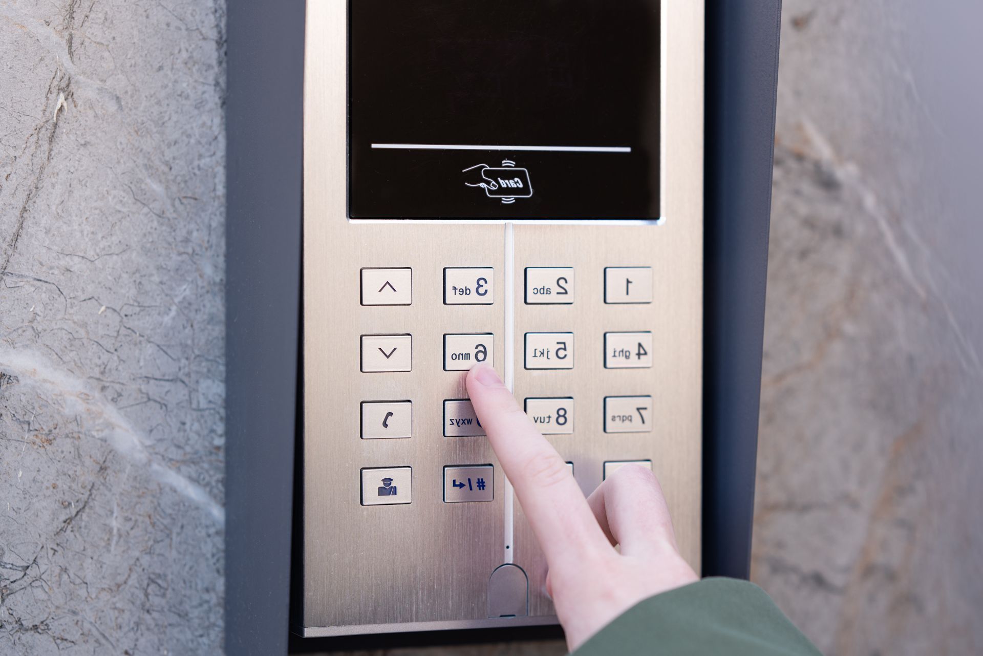 Finger pressing a button on a stainless steel elevator control panel