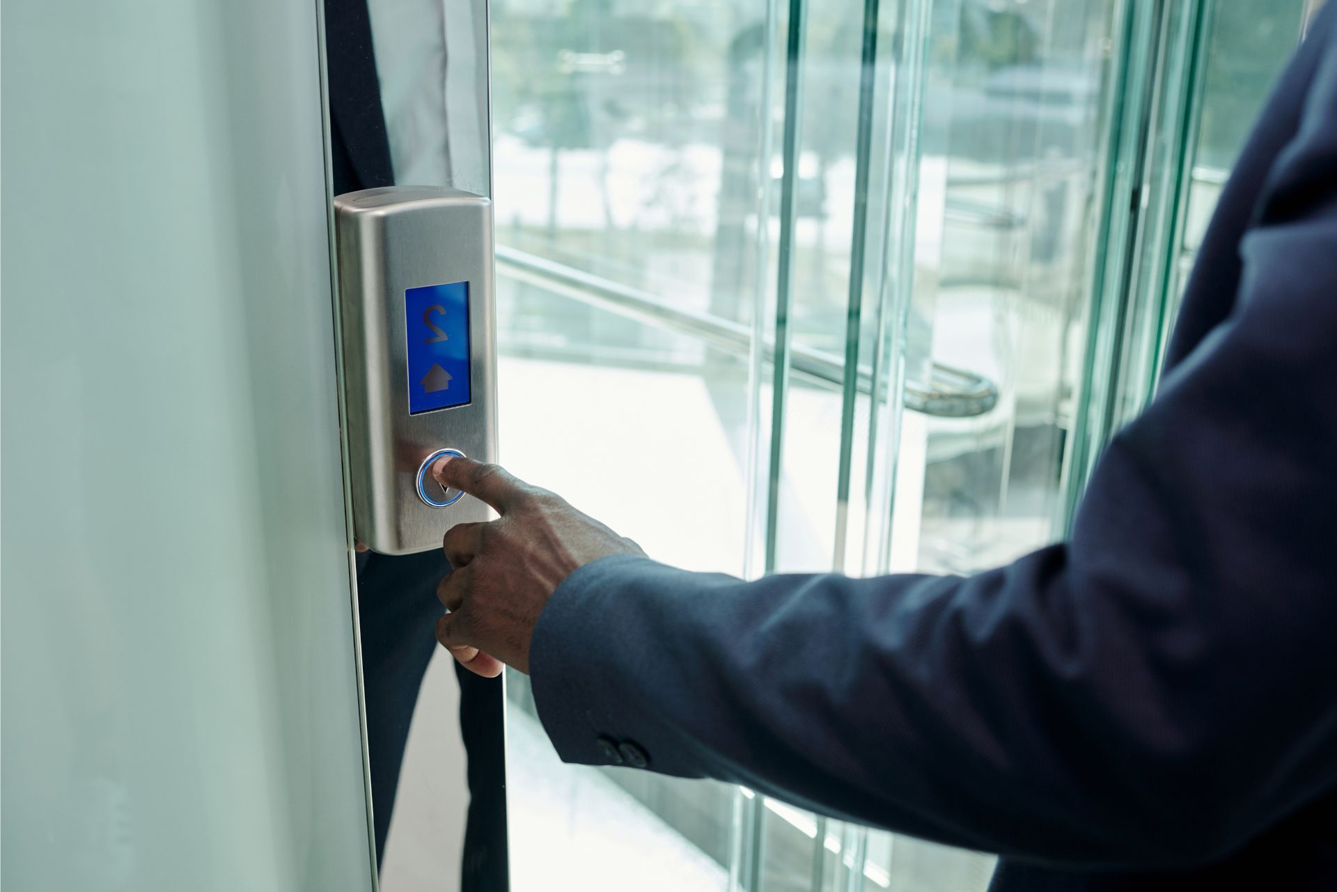Person pressing a fingerprint scanner at a glass entrance door
