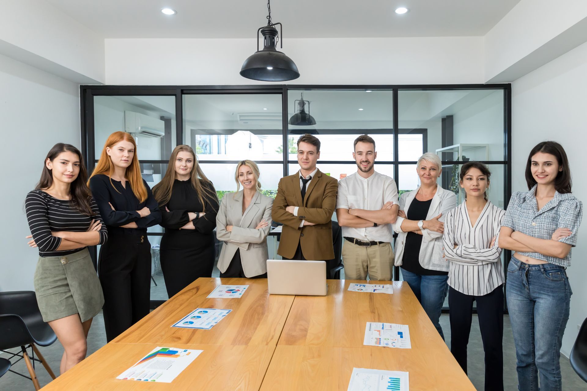 Group of colleagues standing around a conference table in a modern meeting room with glass walls