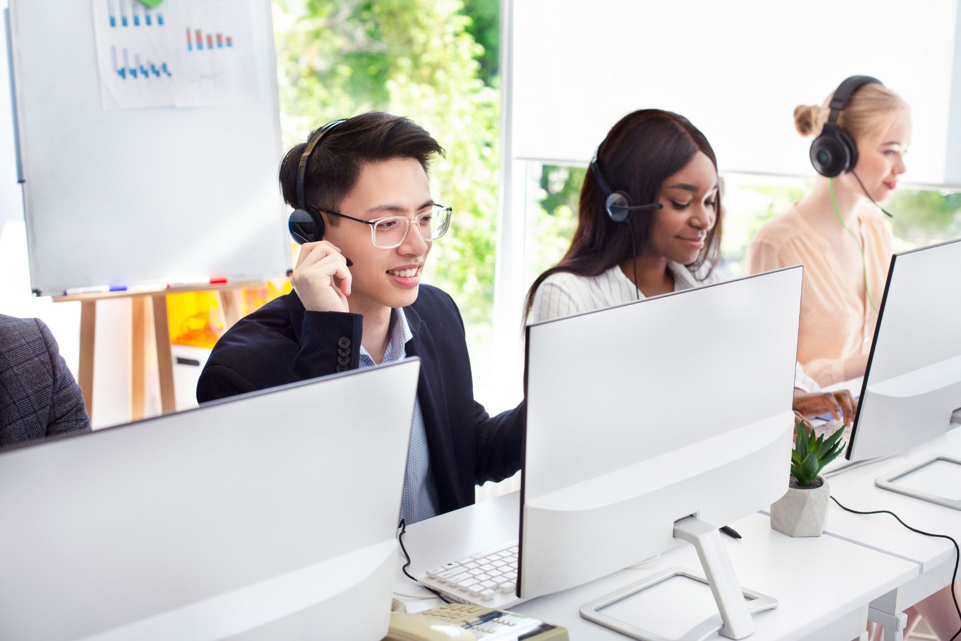 Headset operators working at desktop computers in a bright call center