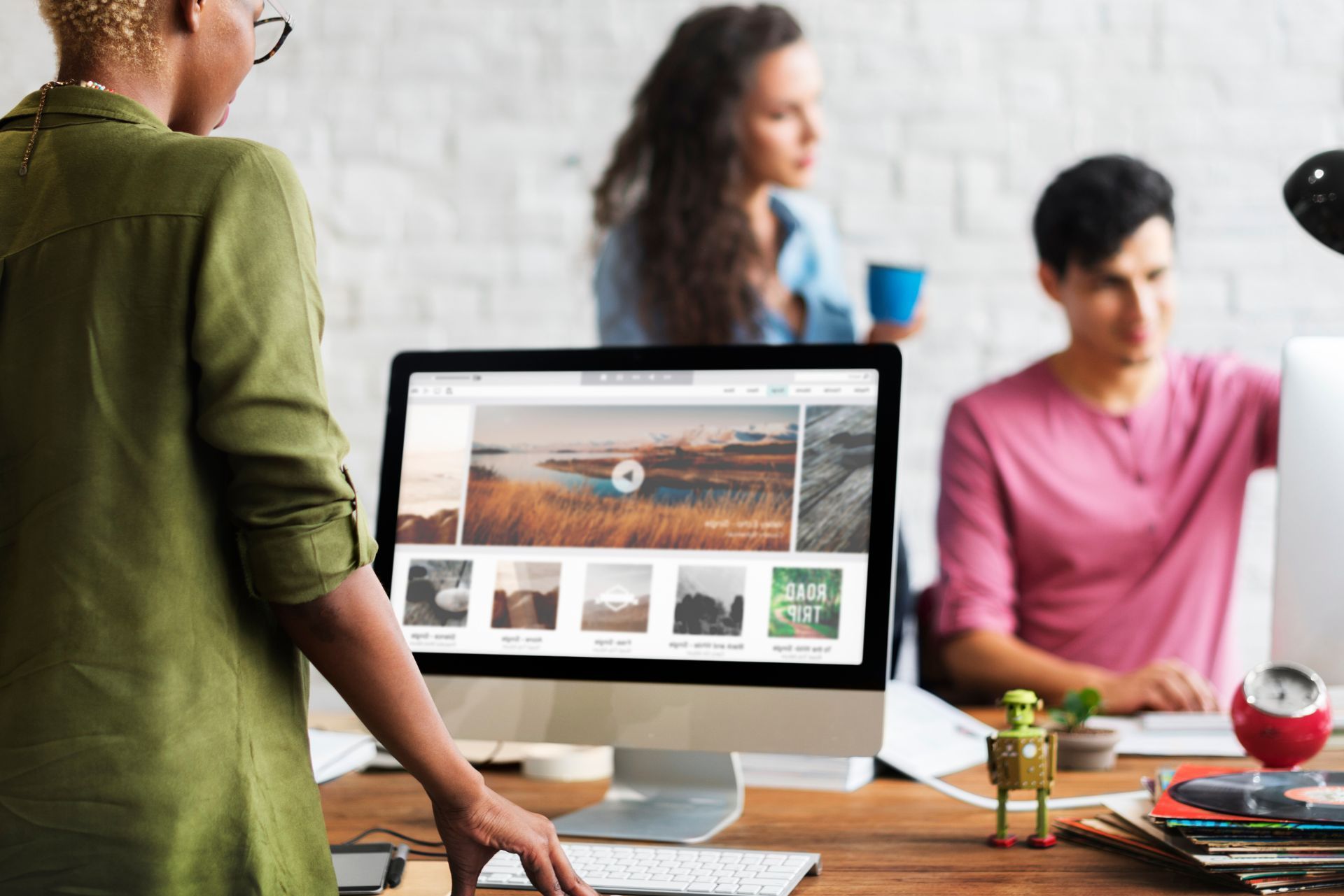 People gathered around a desktop computer in a bright office, reviewing a website on screen.
