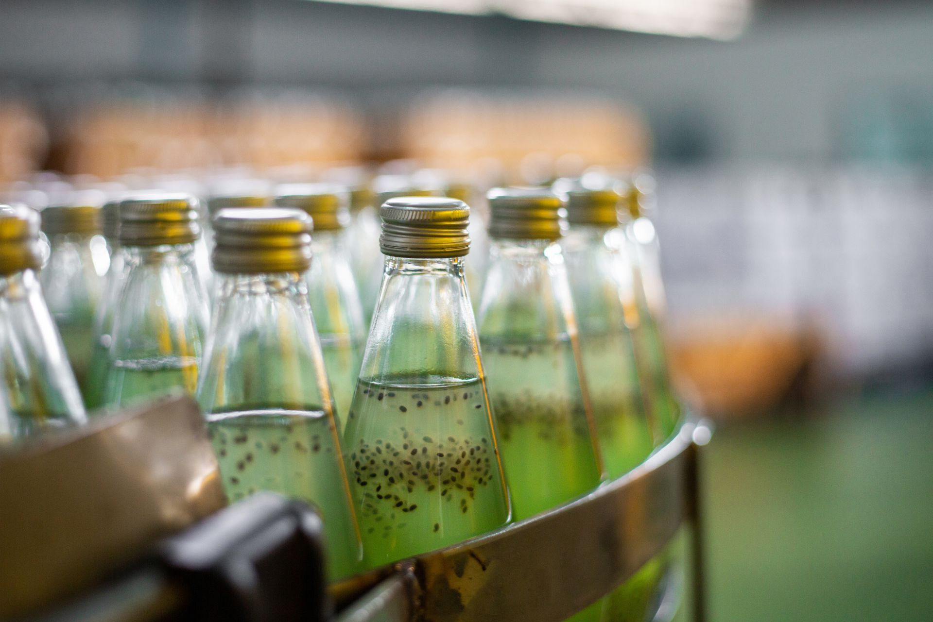 Glass bottles filled with green liquid on a conveyor line in a factory