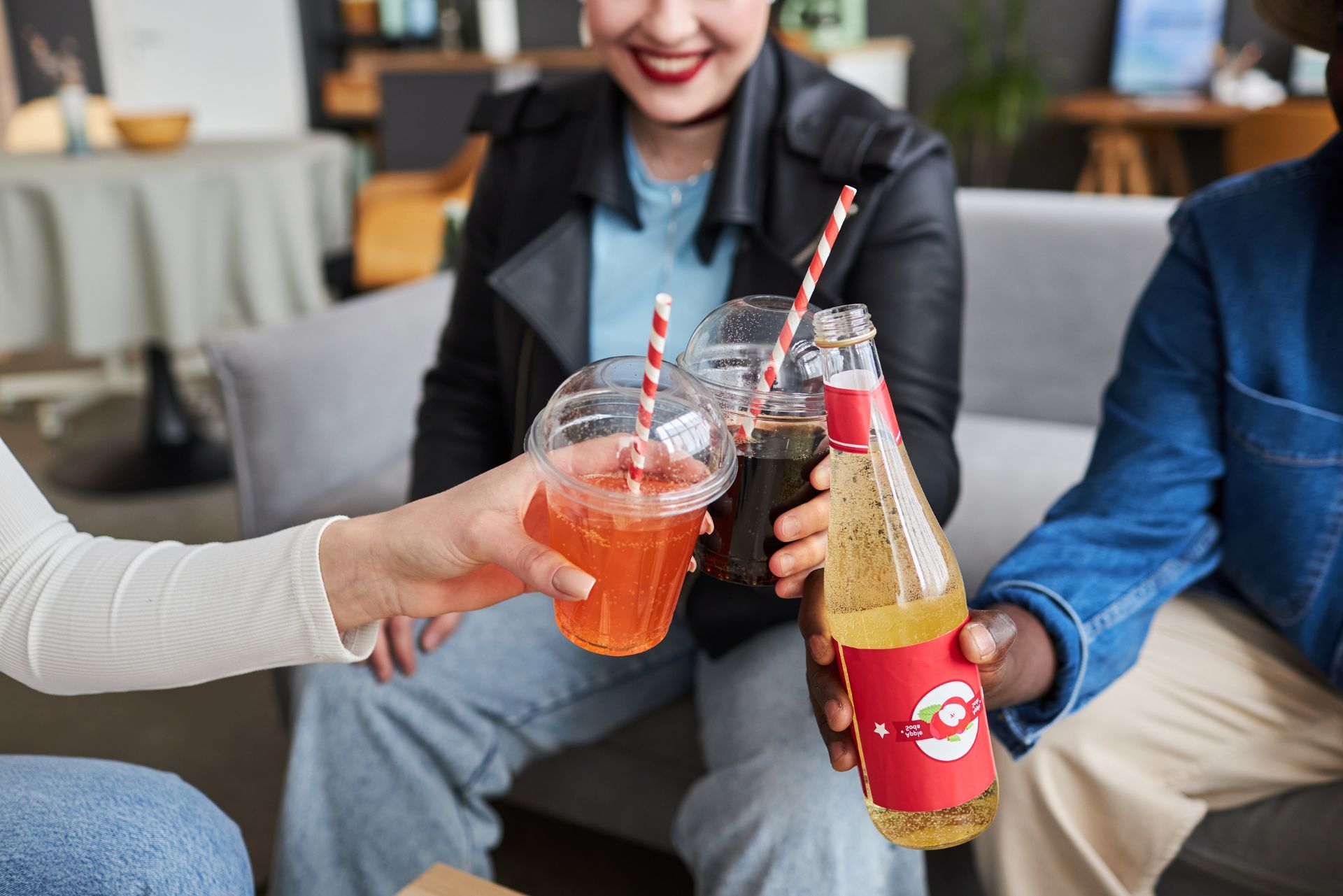 Friends clinking colorful drinks in a casual lounge setting