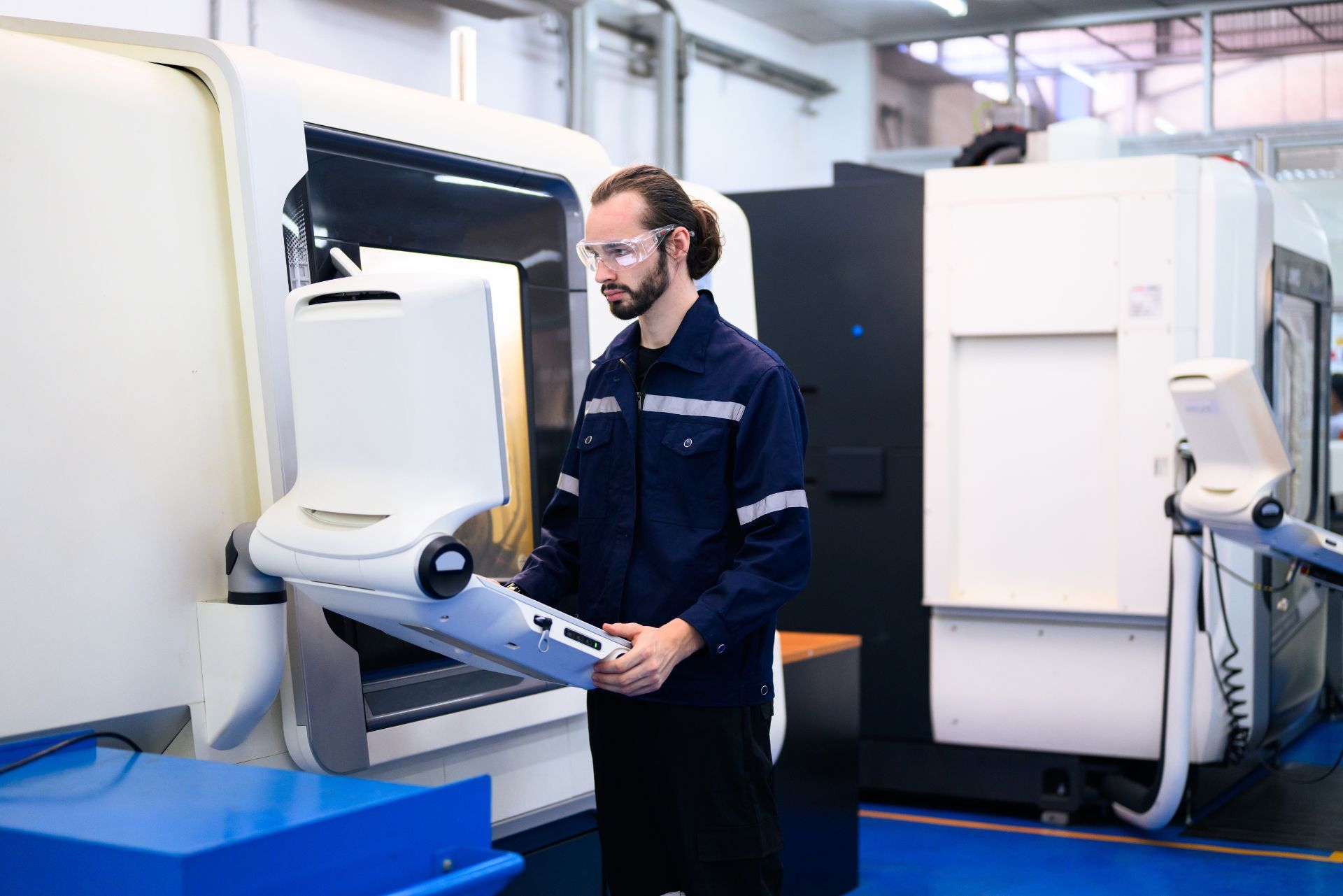 Technician operating a large white industrial machine in a clean manufacturing lab