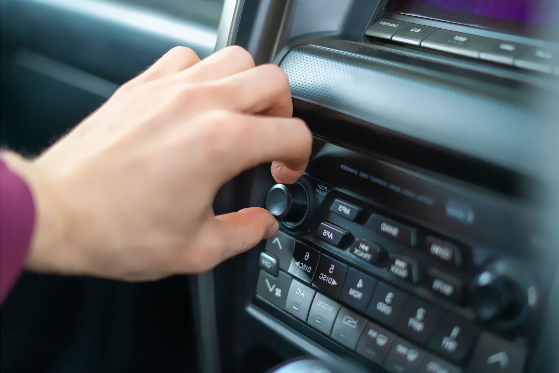 Hand adjusting a car stereo knob on the dashboard