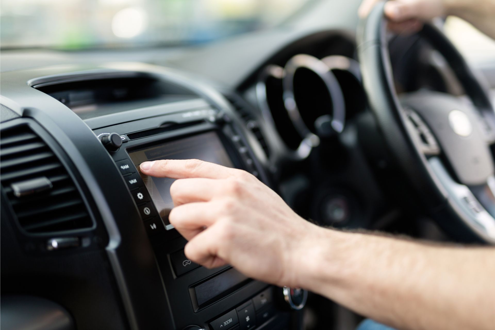 Hand adjusting car stereo controls on a dashboard inside a vehicle