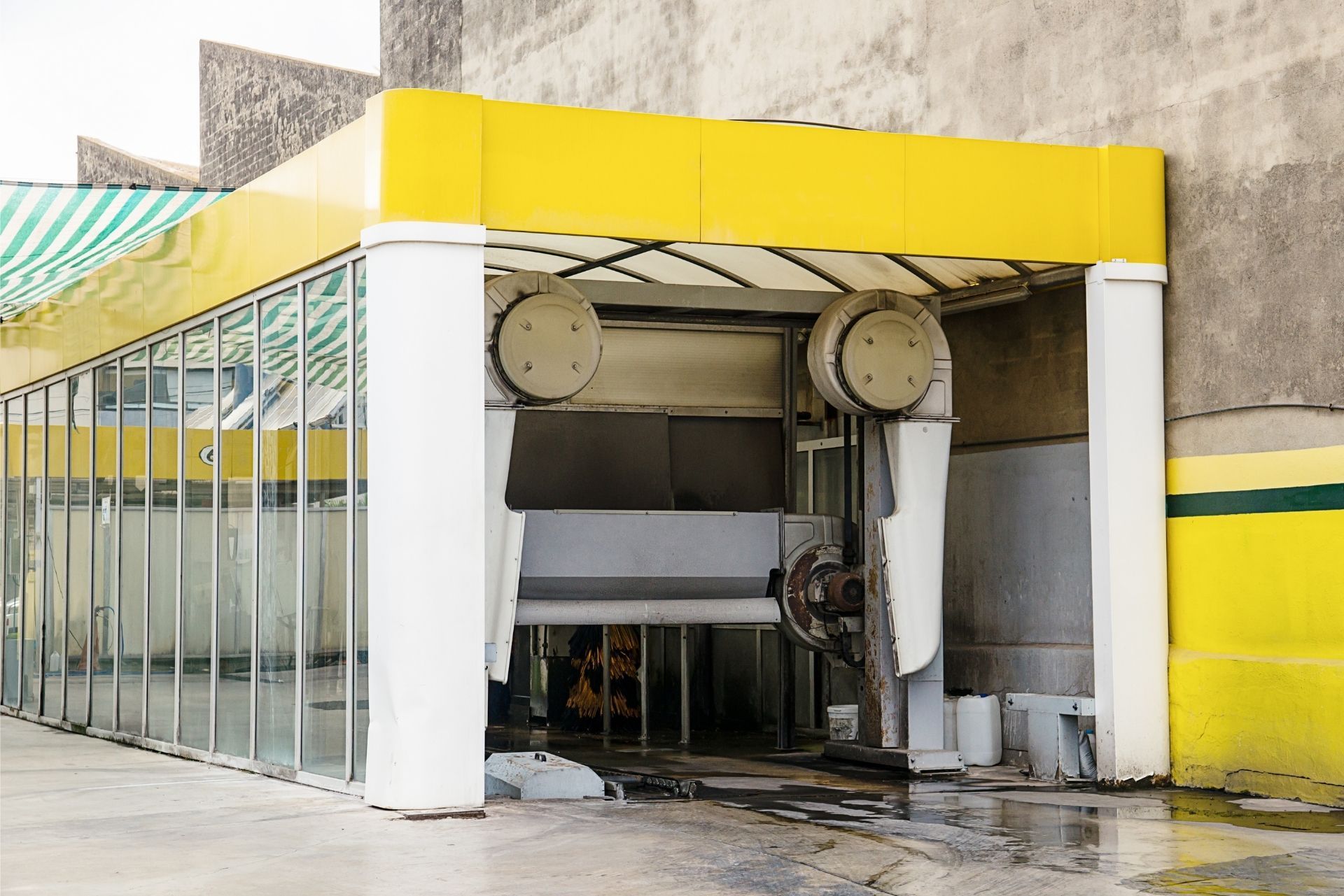 An empty automatic car wash bay with glass walls, a yellow header, and white support columns.