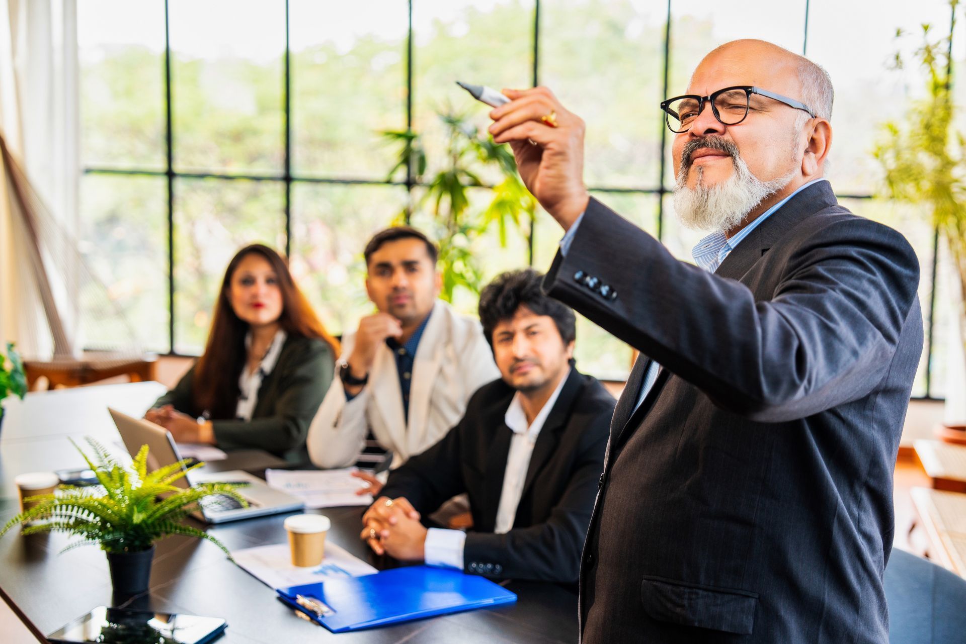 Business meeting with a man presenting to seated colleagues in a bright conference room.