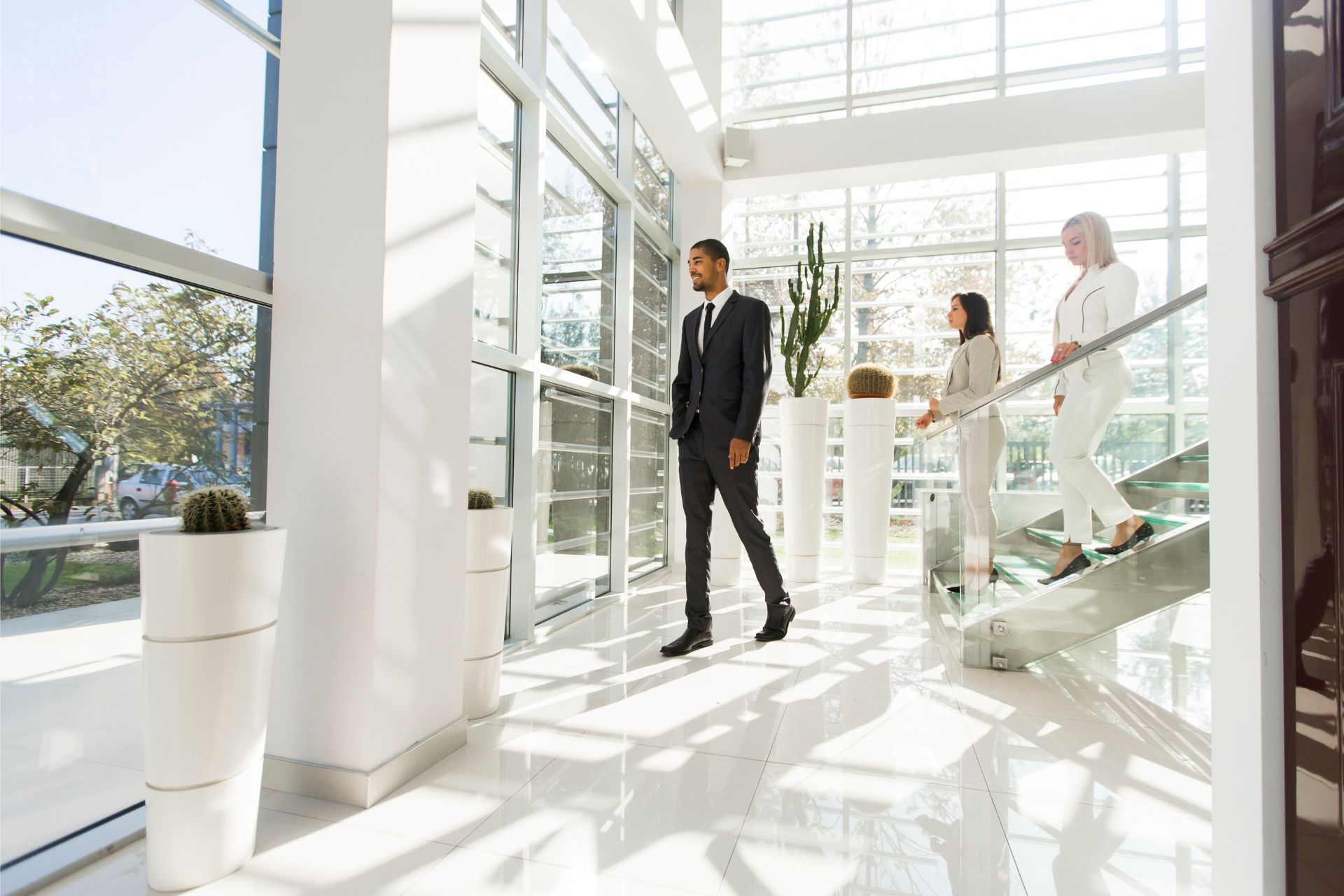 Bright office lobby with people walking through a sunlit glass entrance
