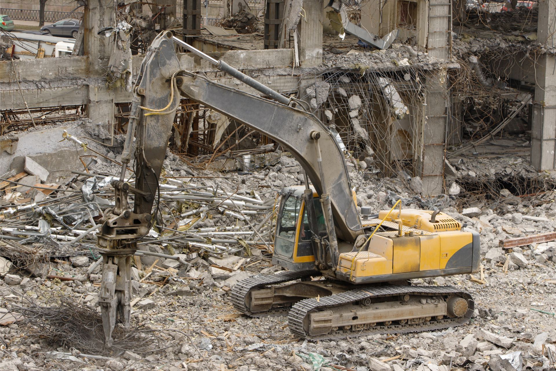 Yellow excavator clearing rubble in a demolished building site