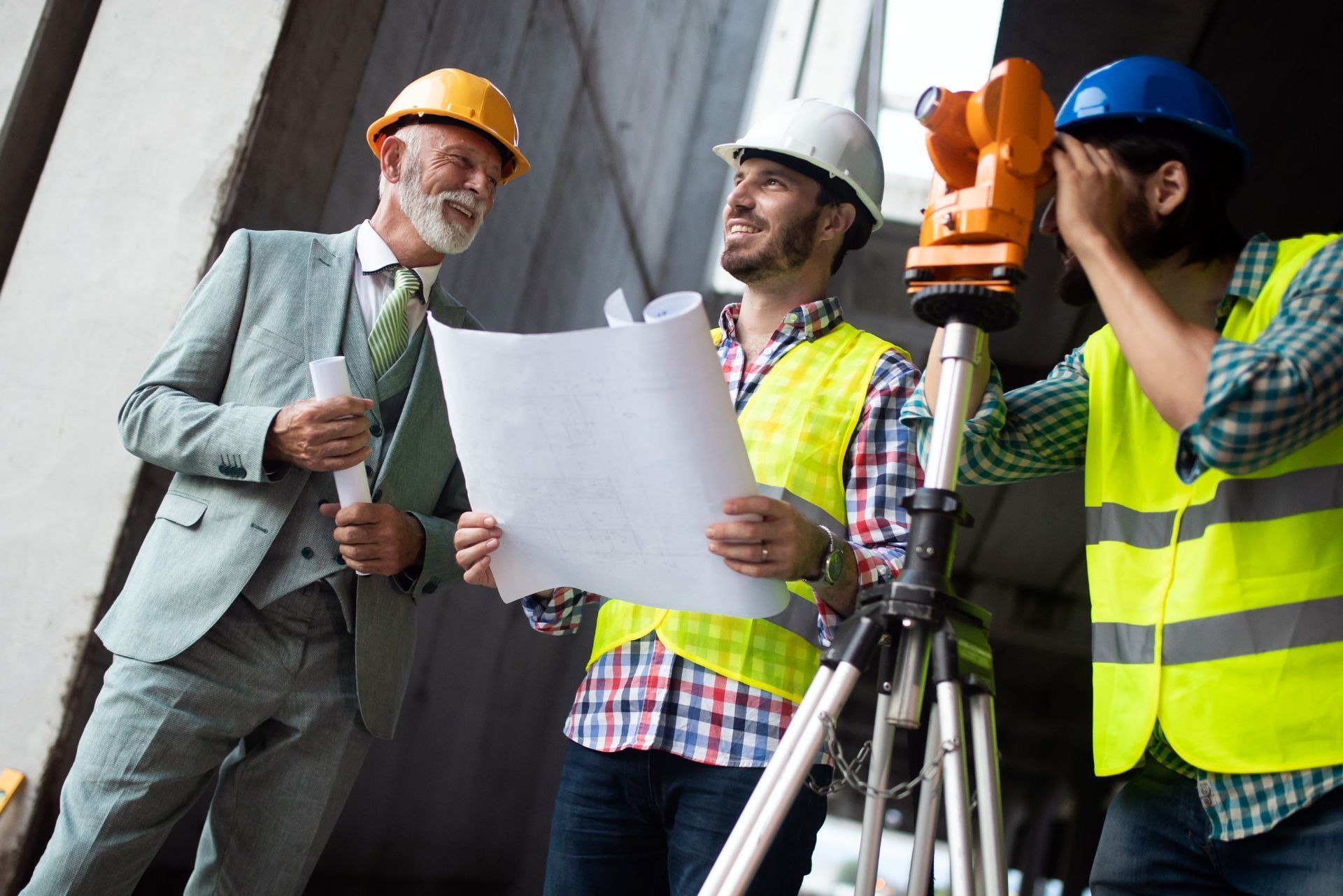 Three construction workers in hard hats reviewing plans at a building site